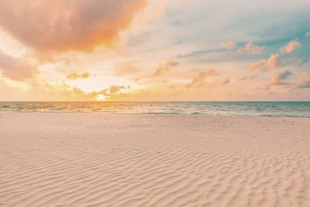Uma praia de areia com ondas e um pôr do sol Uma praia de areia com ondas e um pôr do sol