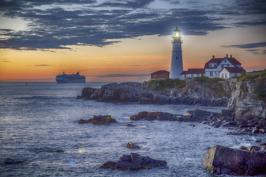 Farol numa costa rochosa com um navio de cruzeiro em fundo