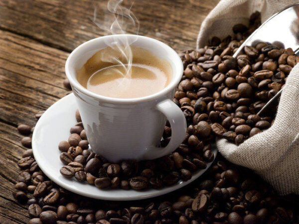 Chávena de café num pires com grãos de café Chávena de café num pires com grãos de café