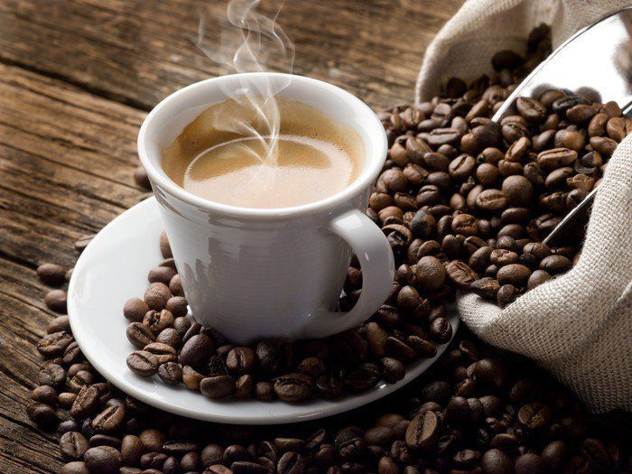 Chávena de café num pires com grãos de café