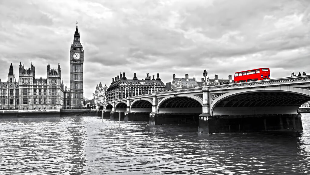 Bridge over water with a clock tower and a red bus